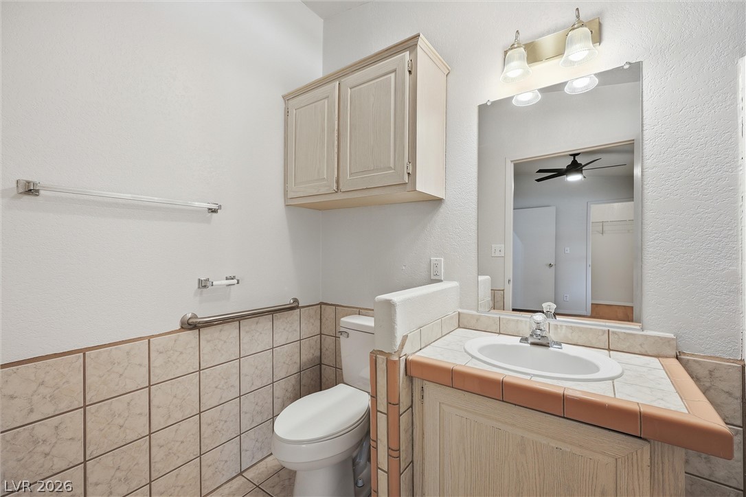 1531 West Harris Farm Road Pahrump, NV 89060 - Photo 29 of 37 Functional bathroom featuring a vanity with a sink and a toilet with grab bars for accessibility.