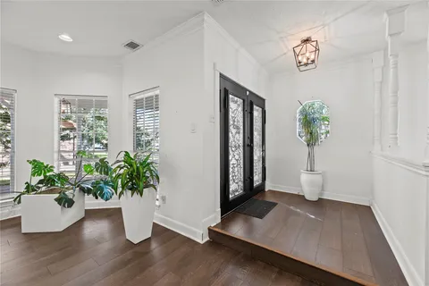 a view of a hallway with wooden floor and a potted plant