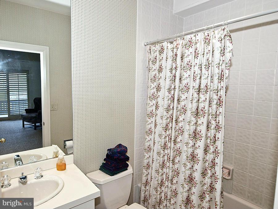10831 Lockland Road Potomac, MD 20854 - Photo 13 of 16 a bathroom with a sink a toilet and shower curtain