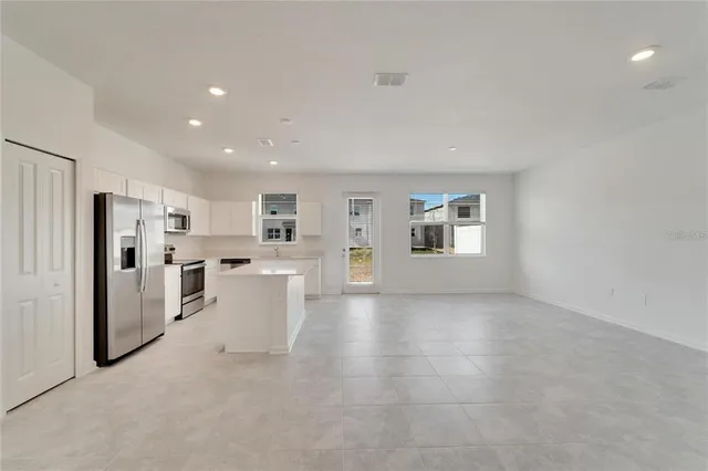 a view of a kitchen with kitchen island and stainless steel appliances