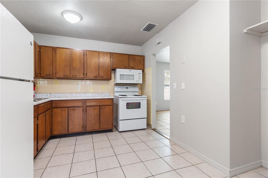 7208 Fair Oaks Street Spring Hill, FL 34606 - Photo 7 of 25 a kitchen with a stove a sink and a refrigerator with wooden cabinets
