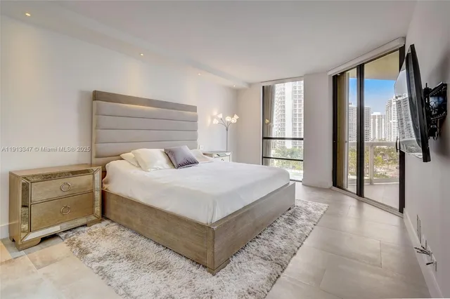 a bedroom with a large bed and a flat tv screen on dresser