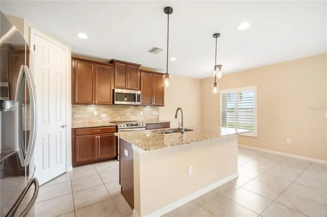 a kitchen with stainless steel appliances granite countertop a sink a stove a refrigerator and island with wooden floor