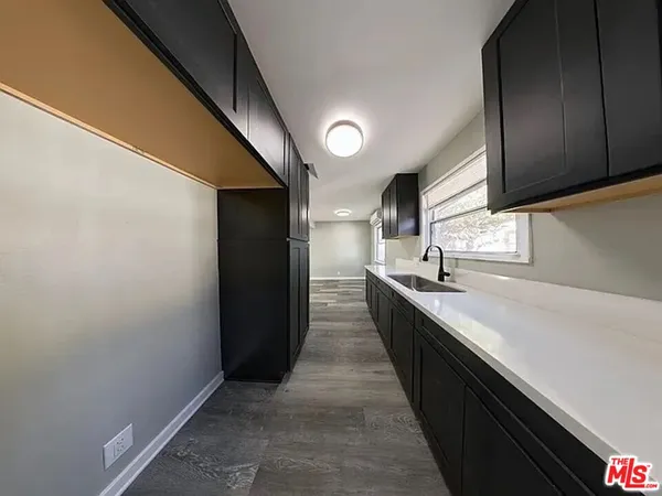 a large kitchen with a sink and dishwasher a stove top oven with wooden floor