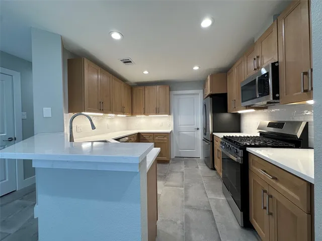 a kitchen with stainless steel appliances granite countertop a stove a sink and a microwave