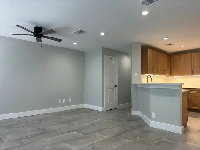 a view of an empty room with a window and a kitchen