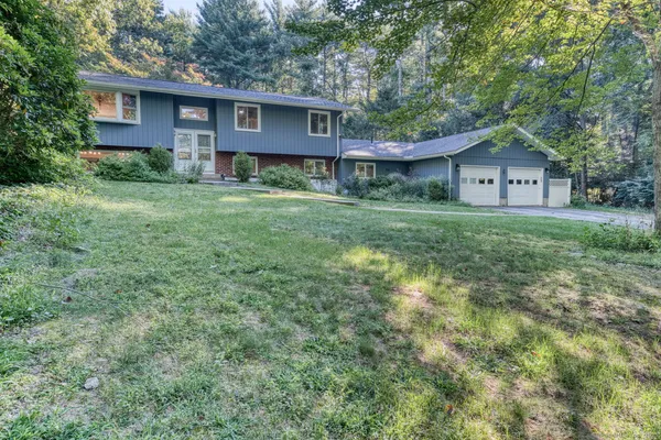 a view of a yard in front of a house with large windows