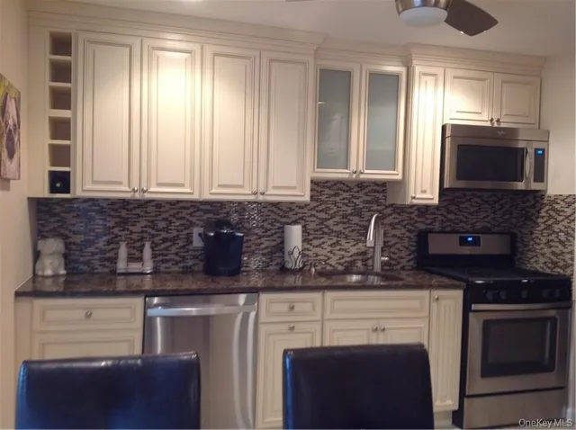 a kitchen with granite countertop a stove a sink and a microwave