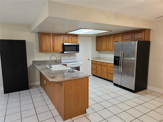 a kitchen with stainless steel appliances granite countertop a sink a microwave a refrigerator and a stove