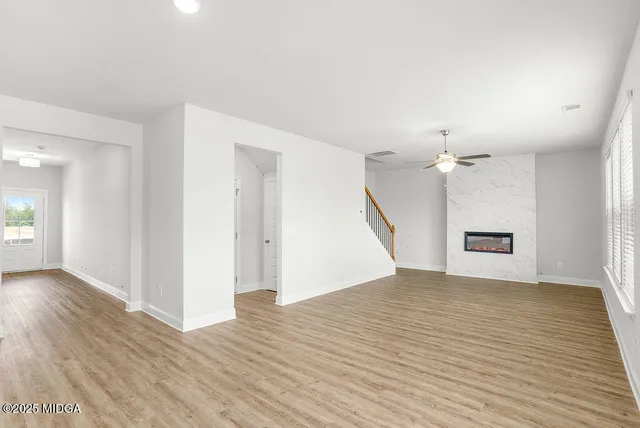 an empty room with wooden floor and ceiling fan