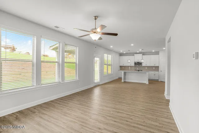 a view of an empty room with a kitchen and wooden floor