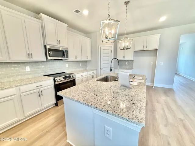 a kitchen with kitchen island granite countertop a sink a counter space appliances and cabinets