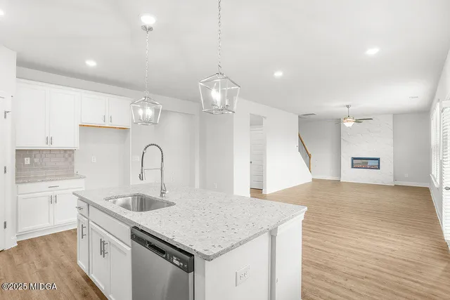 a kitchen with a sink dishwasher a stove a dining table and chairs with wooden floor