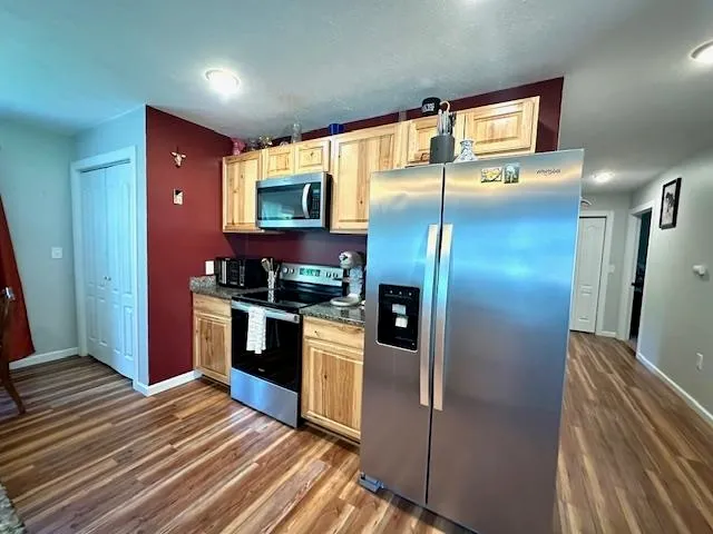 a kitchen with stainless steel appliances kitchen island granite countertop a refrigerator and a sink