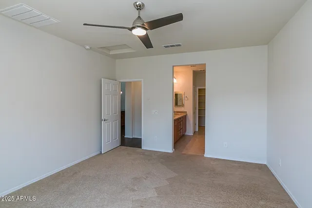 an empty room with closet and a ceiling fan