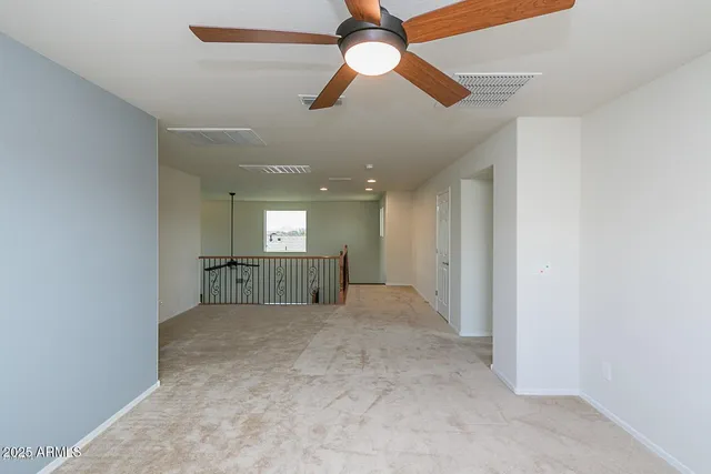 an empty room with chandelier fan and windows