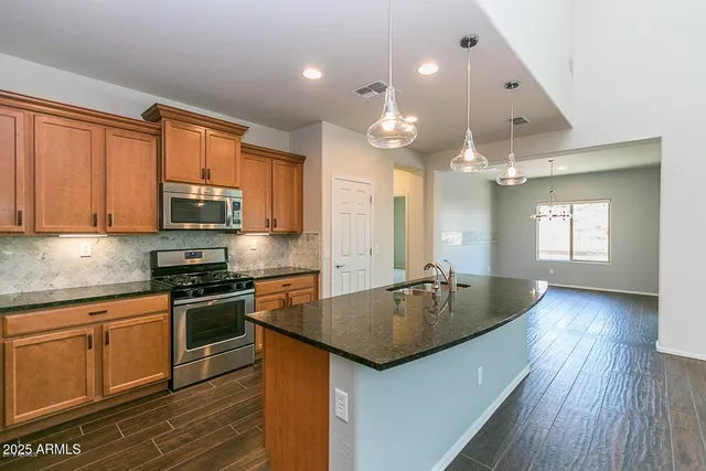 a kitchen with granite countertop a stove a sink dishwasher and a refrigerator with wooden floor