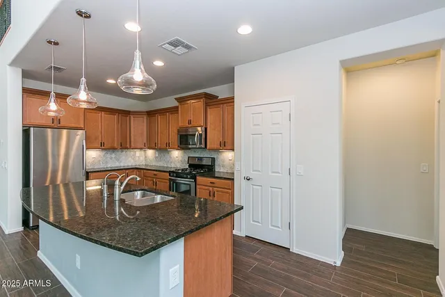 a kitchen with stainless steel appliances granite countertop a sink a refrigerator and a stove top oven