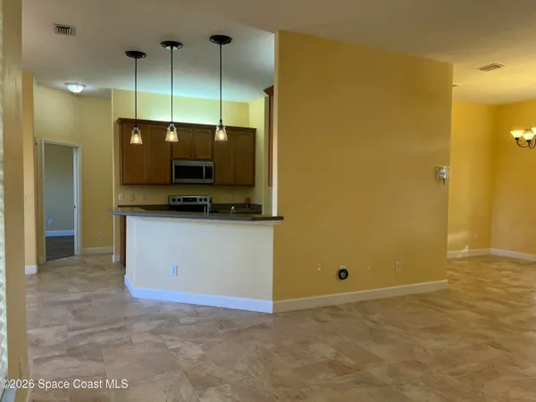 a view of a kitchen with kitchen island a counter top space stainless steel appliances and cabinets
