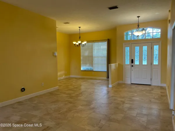 an empty room with chandelier fan and windows