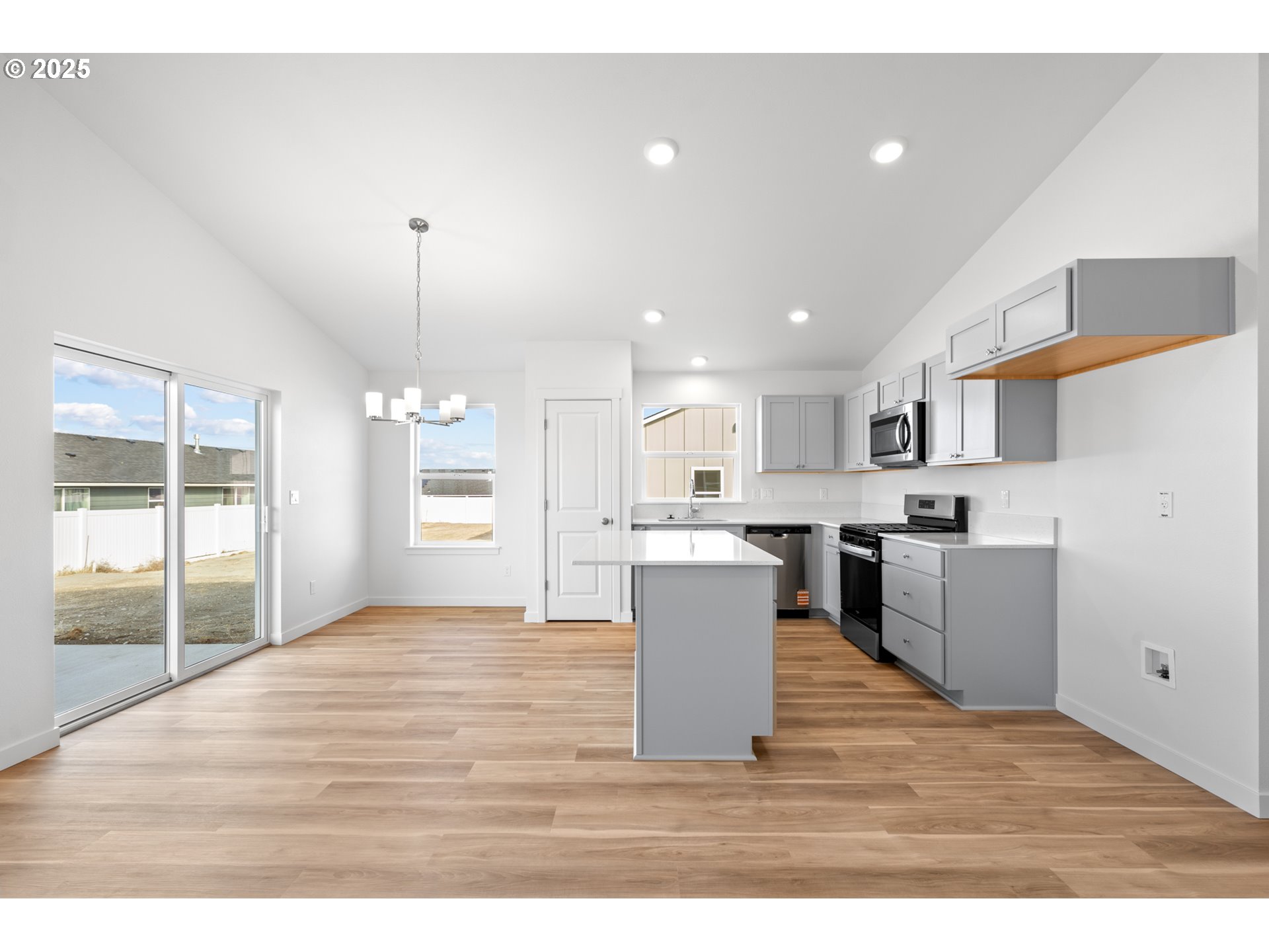 148 Southwest Eagle Drive Boardman, OR 97818 - Photo 4 of 27 a open kitchen with a sink dishwasher a stove and white cabinets with wooden floor