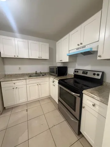 a white kitchen with granite countertop white cabinets and white appliances