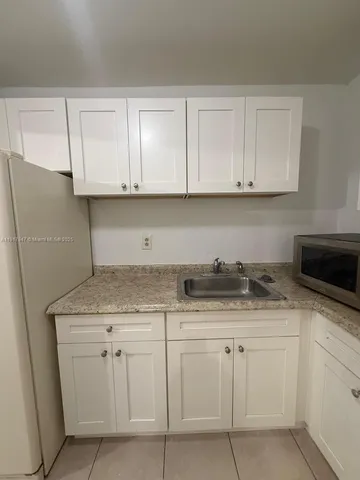 a kitchen with granite countertop white cabinets and a stainless steel appliances