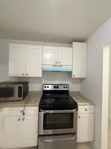 a kitchen with granite countertop white cabinets and stainless steel appliances