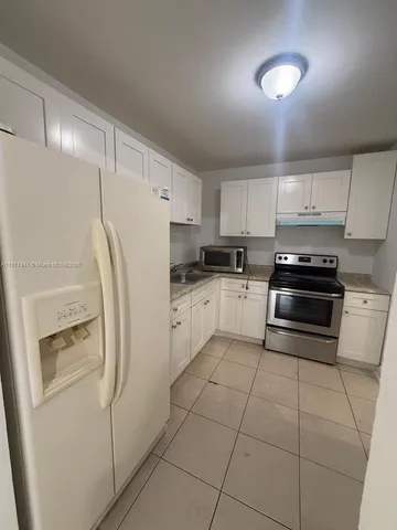 a kitchen with cabinets and a refrigerator