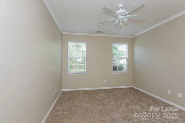 an empty room with windows and ceiling fan
