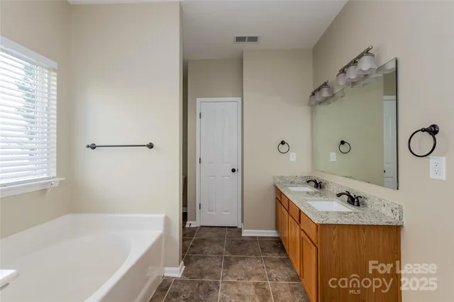 a bathroom with a tub a sink a mirror and a shower