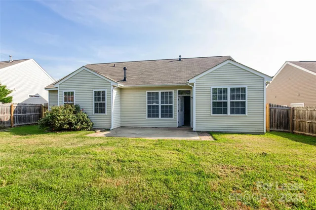 a house that has a big yard with plants and trees in front of it