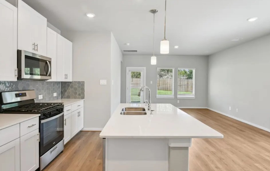 a kitchen with stainless steel appliances a kitchen island a stove a cabinets and a wooden floor
