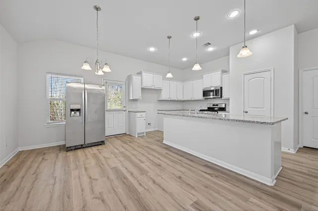a kitchen with a white wooden cabinets counter top space and stainless steel appliances