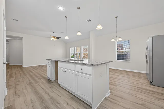 a kitchen with kitchen island sink stove and white cabinets with wooden floor