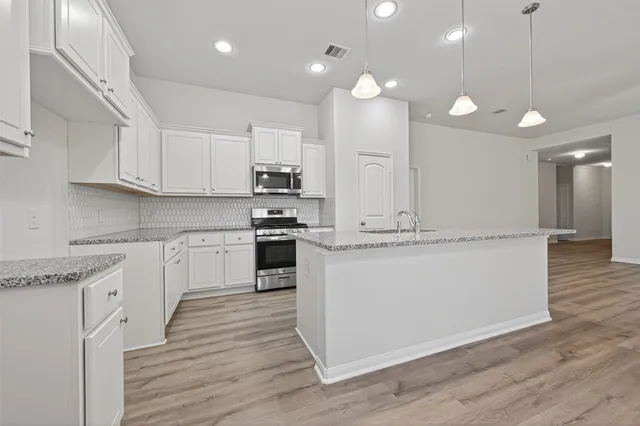 a large kitchen with kitchen island a sink a center island stainless steel appliances and a cabinets