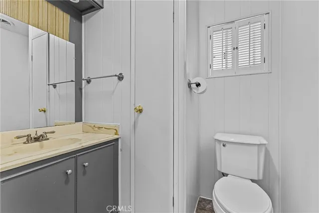 a bathroom with a granite countertop toilet sink and mirror