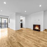 a view of an empty room with wooden floor and a fireplace