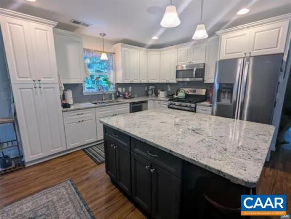 a kitchen with stainless steel appliances granite countertop a sink refrigerator and cabinets