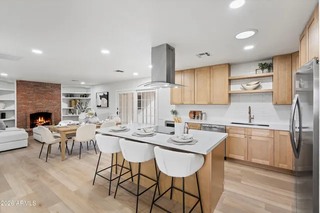 a kitchen with stainless steel appliances kitchen island granite countertop a stove a sink a dining table and chairs