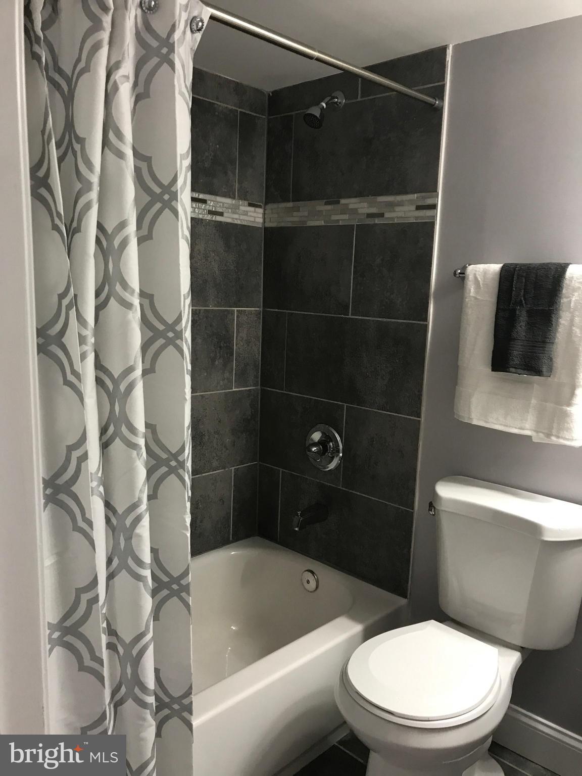 1441 Walker Avenue Baltimore, MD 21239 - Photo 14 of 28 a white toilet and tub sitting next to a bathroom sink