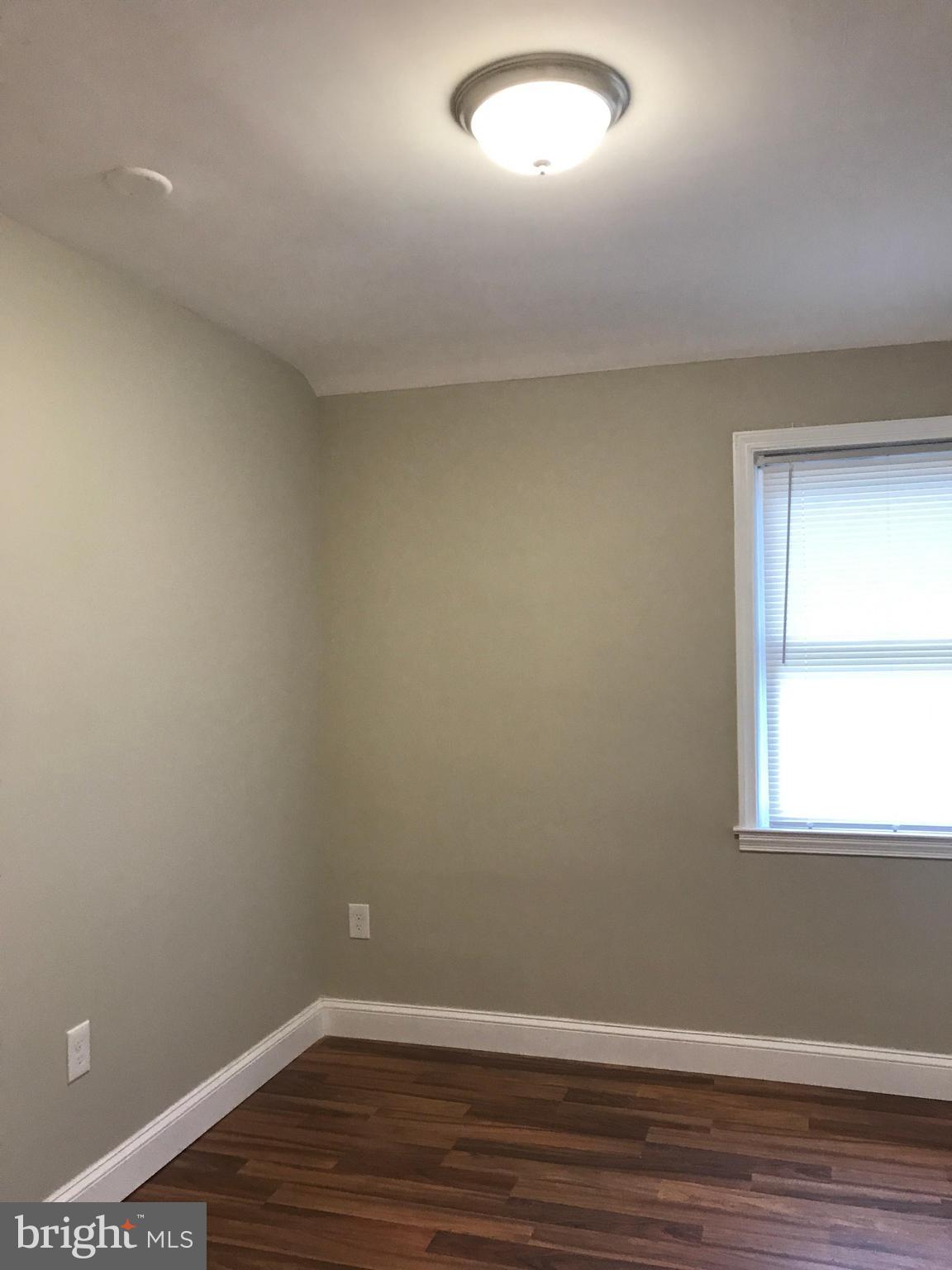 1441 Walker Avenue Baltimore, MD 21239 - Photo 27 of 28 an empty room with wooden floor and windows