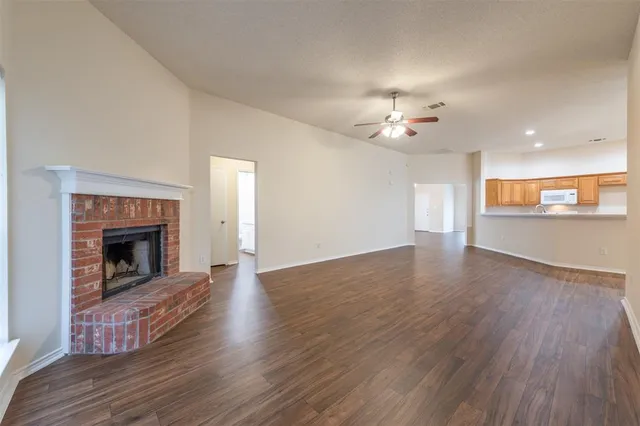 a view of an empty room with wooden floor fireplace and a window