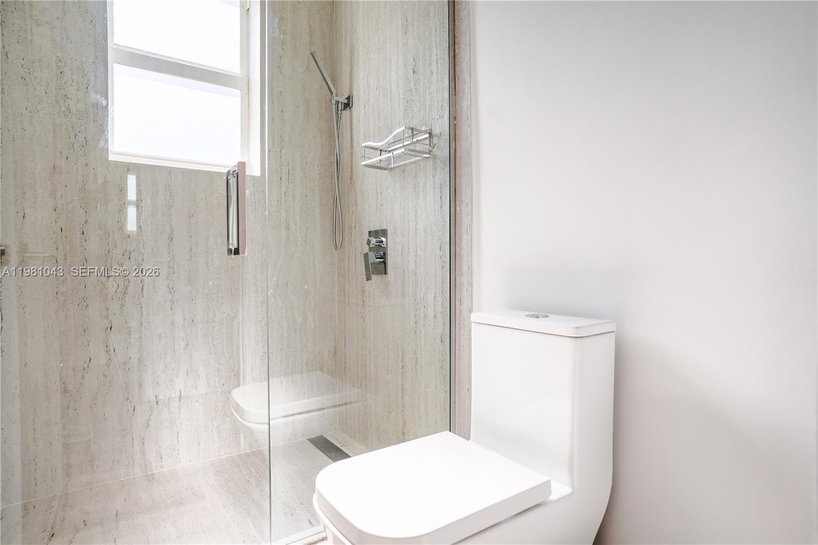 136 Northeast 46th Street, Unit 3 Miami, FL 33137 - Photo 8 of 9 a white toilet sitting next to a bathroom sink and shower