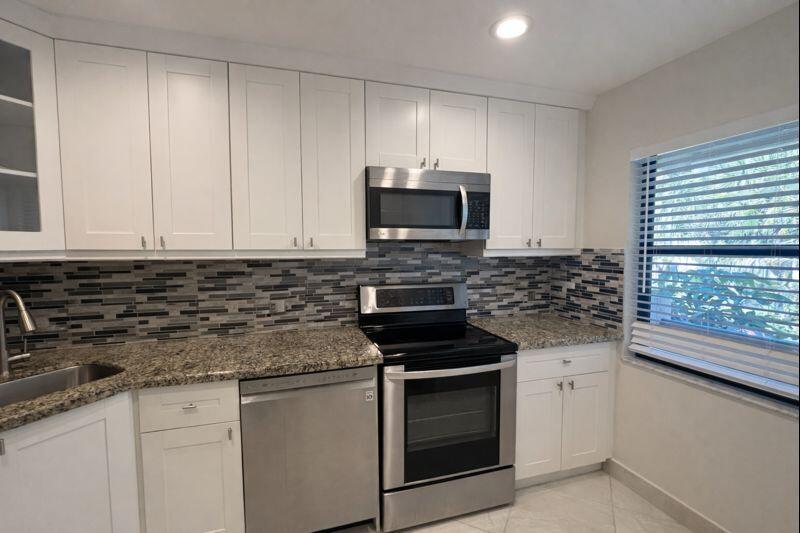 21851 Arriba Real, Unit L Boca Raton, FL 33433 - Photo 5 of 26 a kitchen with granite countertop white cabinets and stainless steel appliances