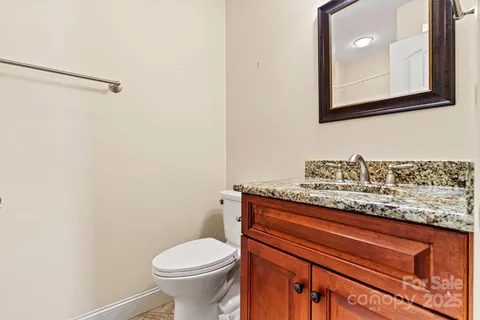 a bathroom with a granite countertop toilet and a sink