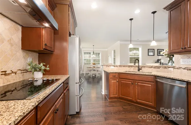 a kitchen with stainless steel appliances granite countertop a stove a sink and a wooden floors