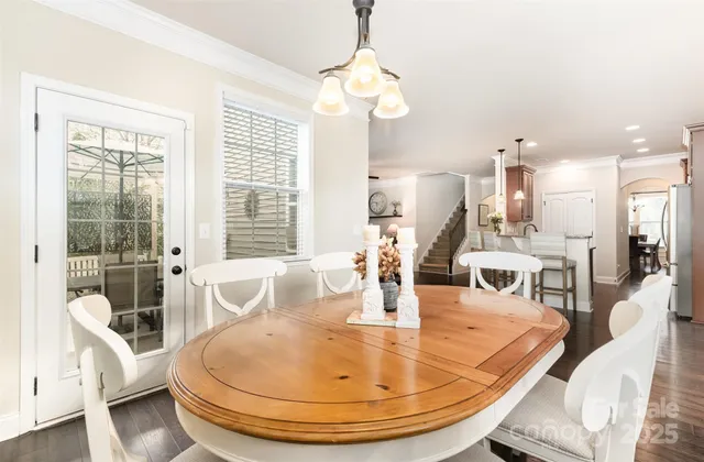 a dining room with wooden floor a chandelier a wooden table and chairs