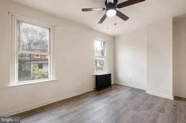 a view of an empty room with a window and wooden floor