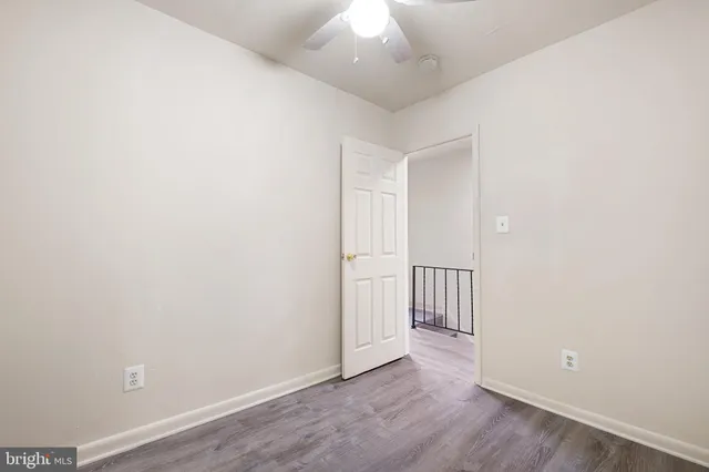 an empty room with wooden floor and ceiling fan